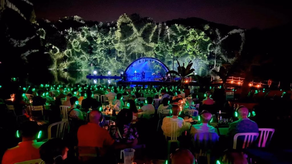 Concert de nuit au bord de la Meuse, à Namur, public assis équipé de casques sans fil lumineux, sans aucune enceinte